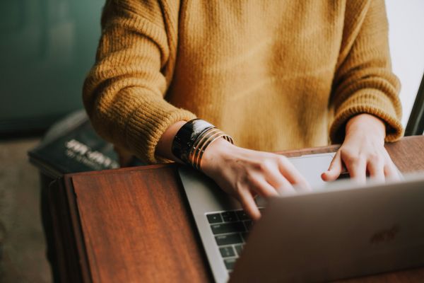 A person taking notes next to a computer